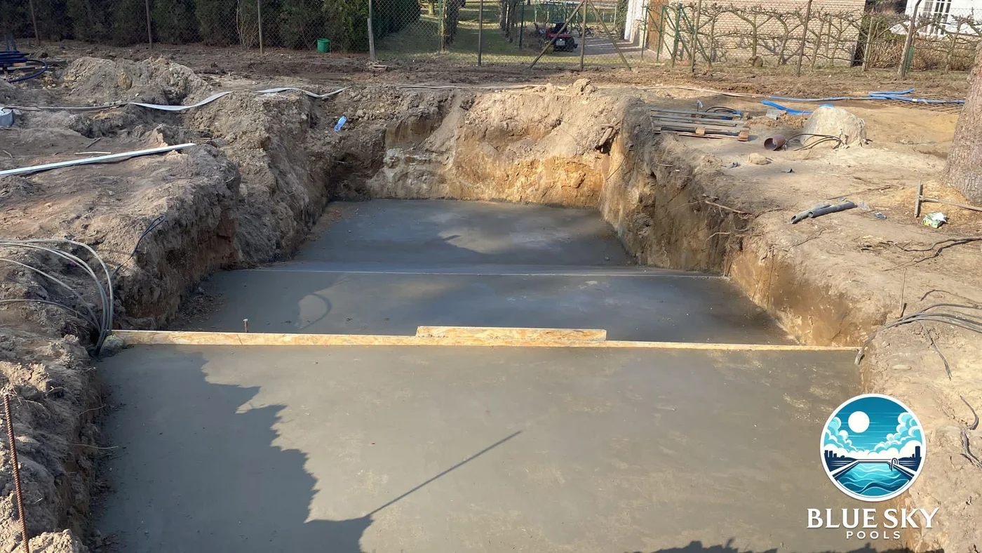 Etap wylewania płyty dennej z betonem — widoczne szalunki i instalacje techniczne