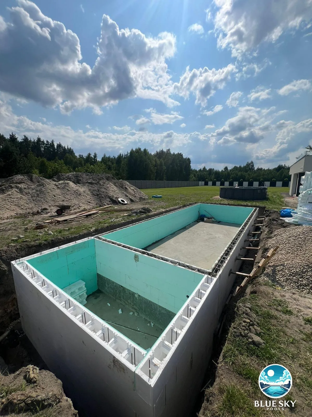 Budowa basenu betonowego z turkusową folią — ściany żelbetowe i technika basenowa w trakcie montażu