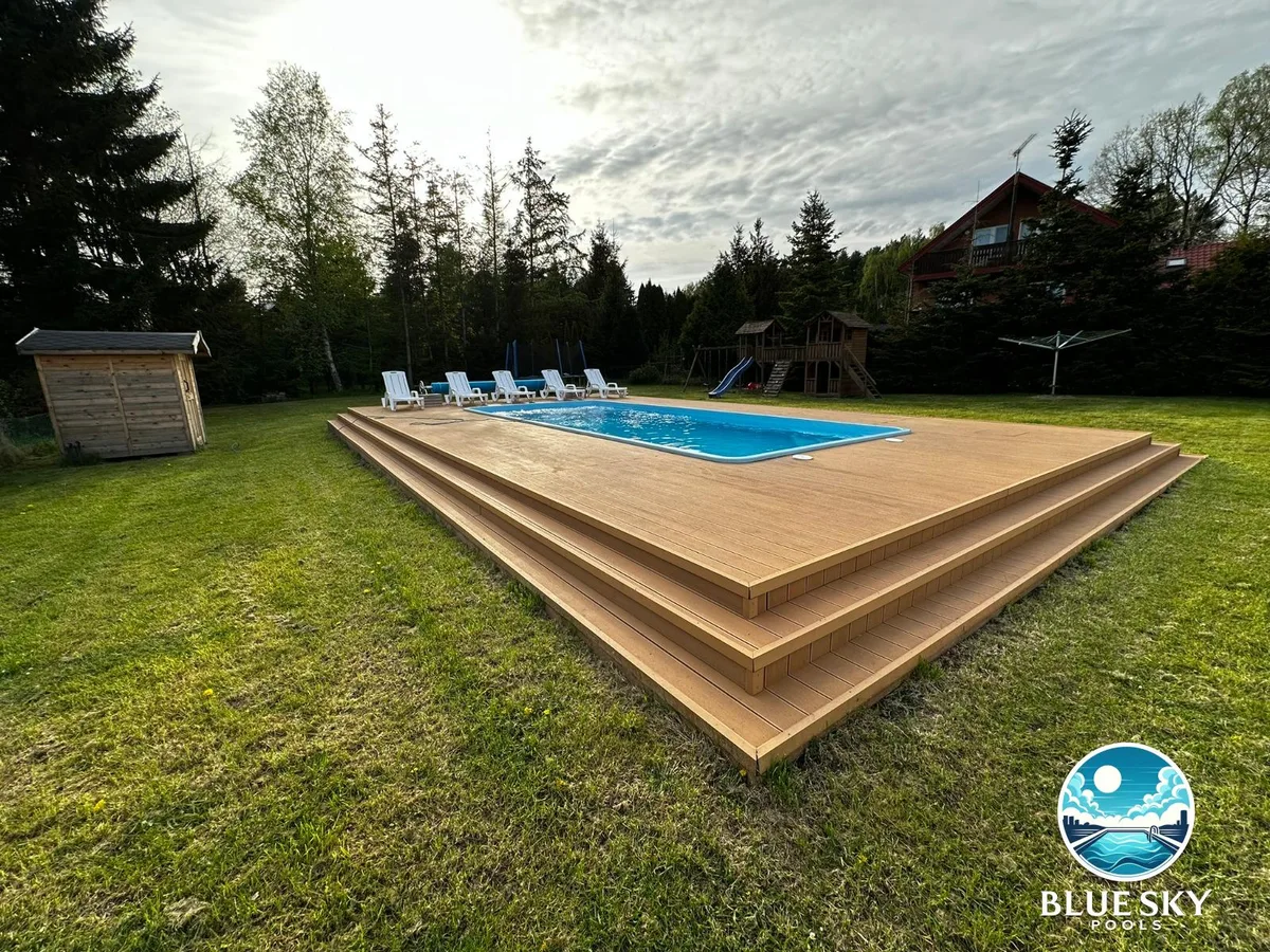 Basen betonowy z drewnianym tarasem i niebieską folią basenową