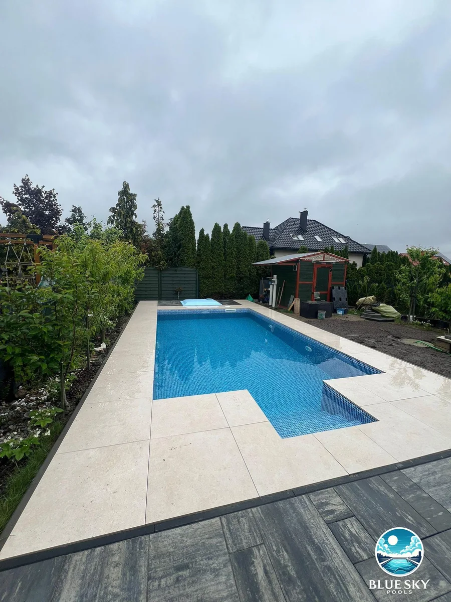 Basen betonowy z jacuzzi, bezowe płyty tarasowe i zieleń